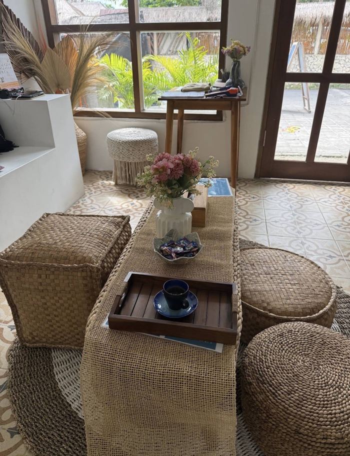 Reception area with woven poufs, fresh flowers and a garden view