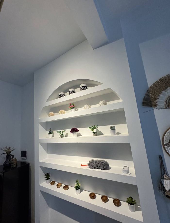 Arched white display shelves with plants and wooden bowls